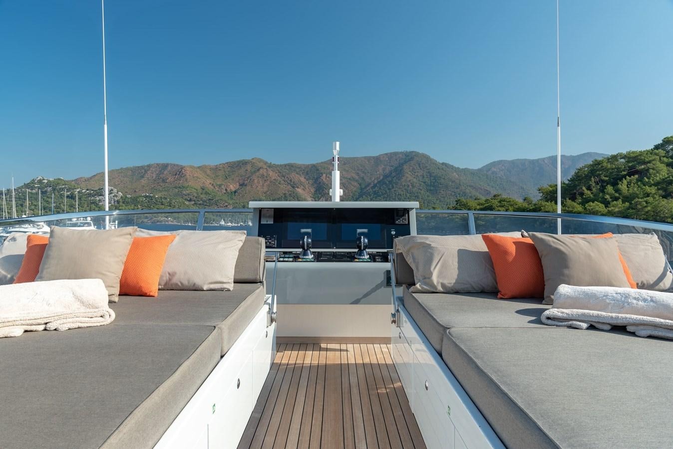 a deck with beds and a large mountain in the background aboard ASYA Yacht for Sale