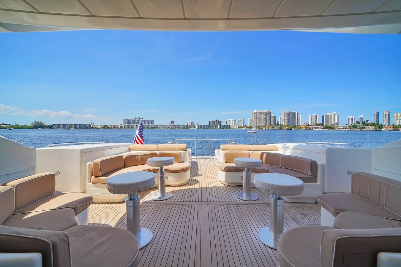 a deck with chairs and tables on it by a body of water aboard 108' MANGUSTA 2002 Yacht for Sale