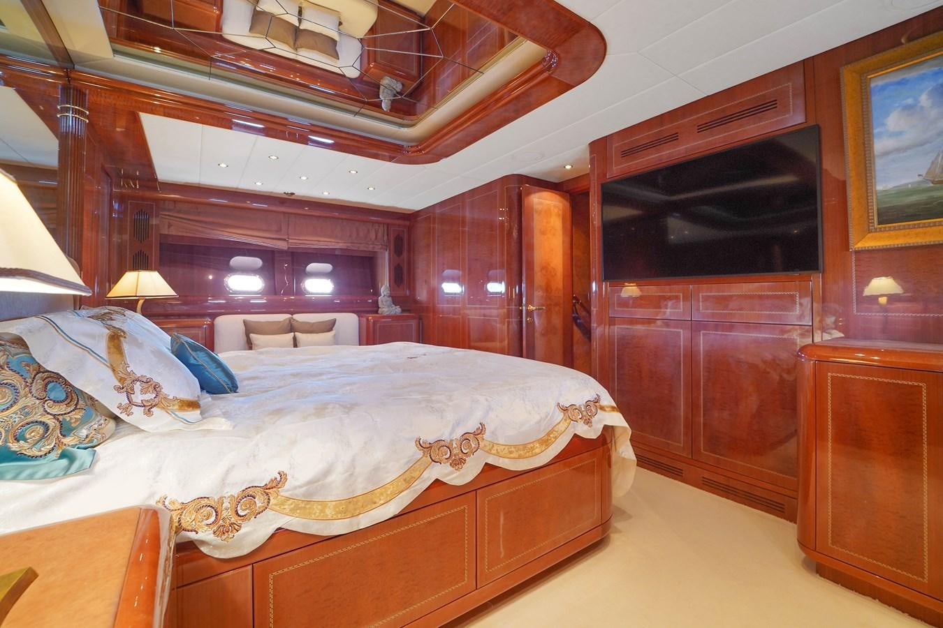 a bedroom with a bed and a wood cabinet aboard 108' MANGUSTA 2002 Yacht for Sale
