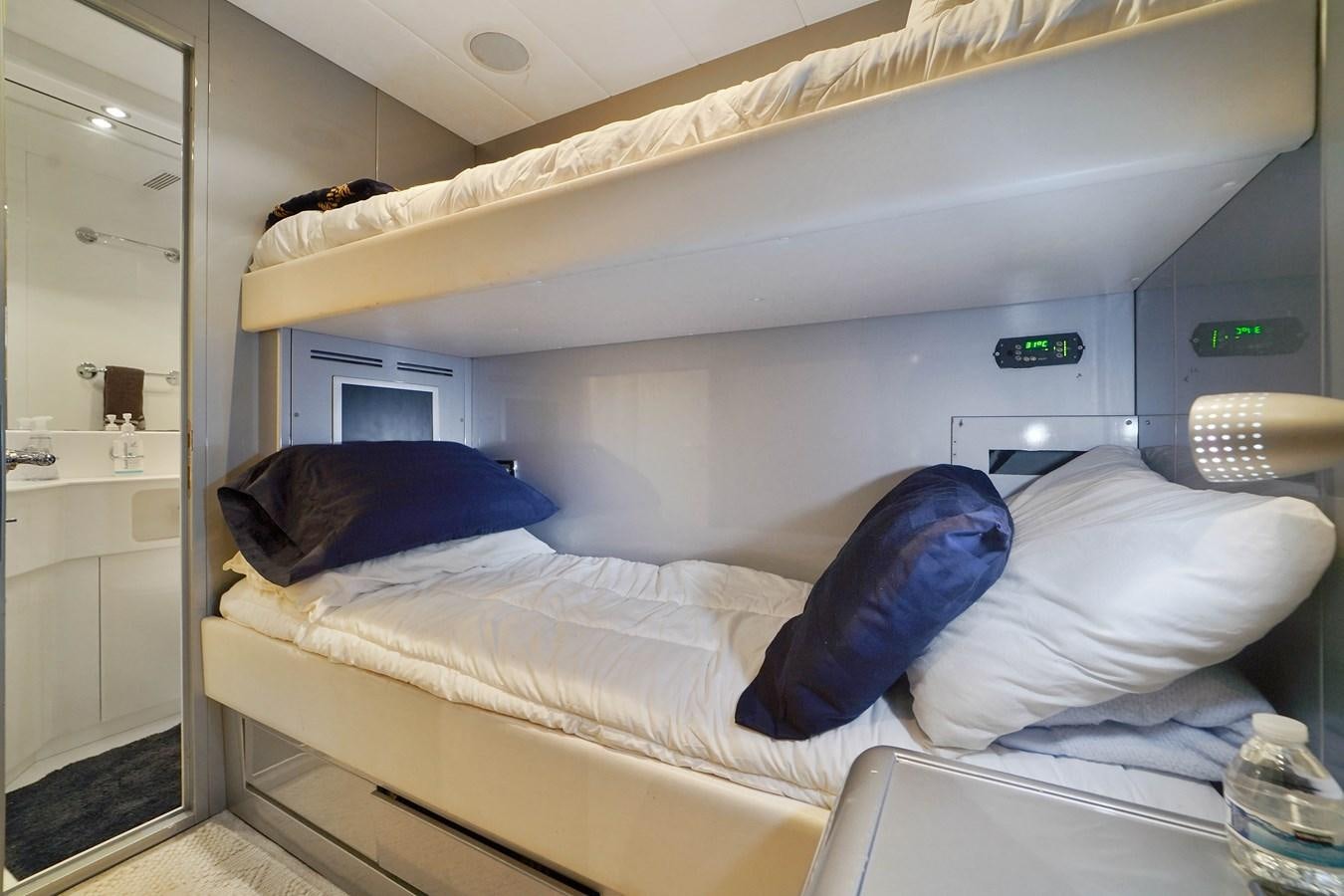 a bed with a white sheet and blue pillow on it aboard 108' MANGUSTA 2002 Yacht for Sale