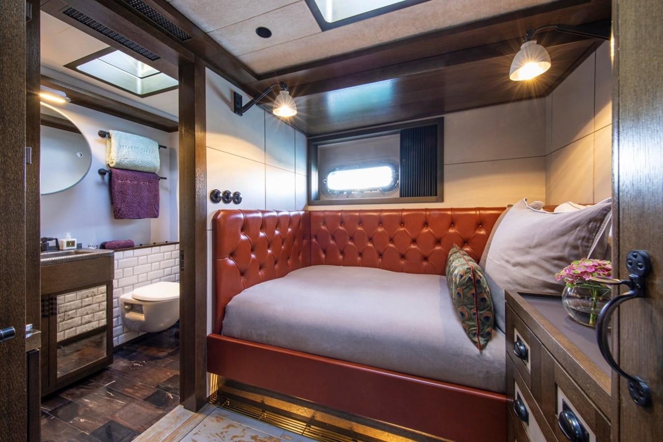 a bedroom with a bed and a dresser aboard PINK GIN Yacht for Sale