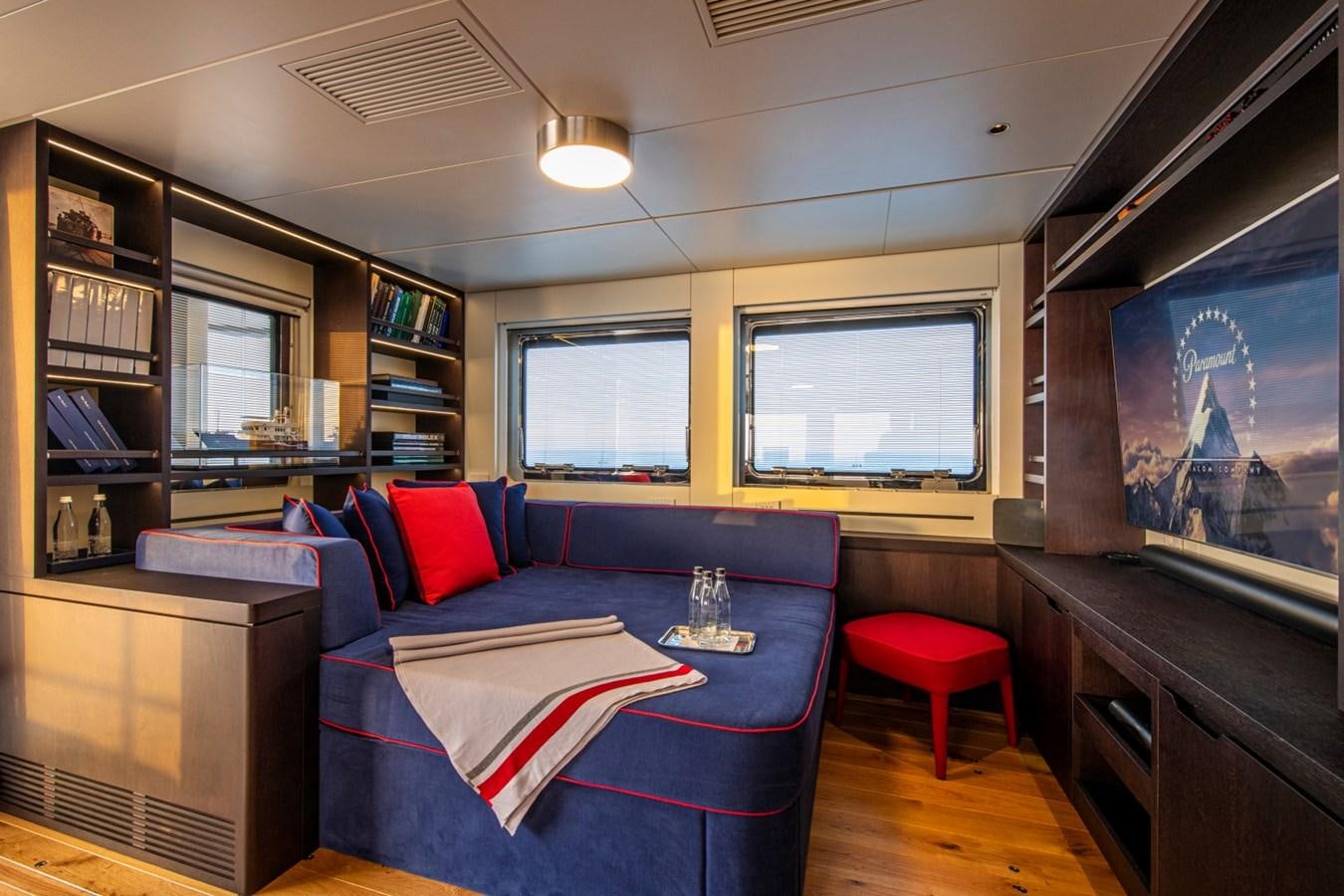 a room with a blue couch and a red stool aboard AUDACE Yacht for Sale