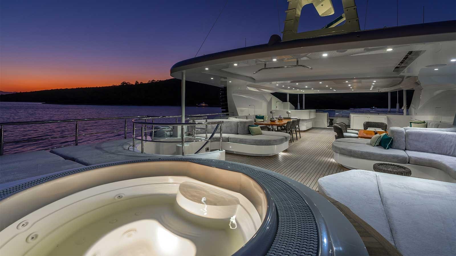 a large white lounge chair on a deck overlooking a large body of water aboard IMMERSIVE Yacht for Sale