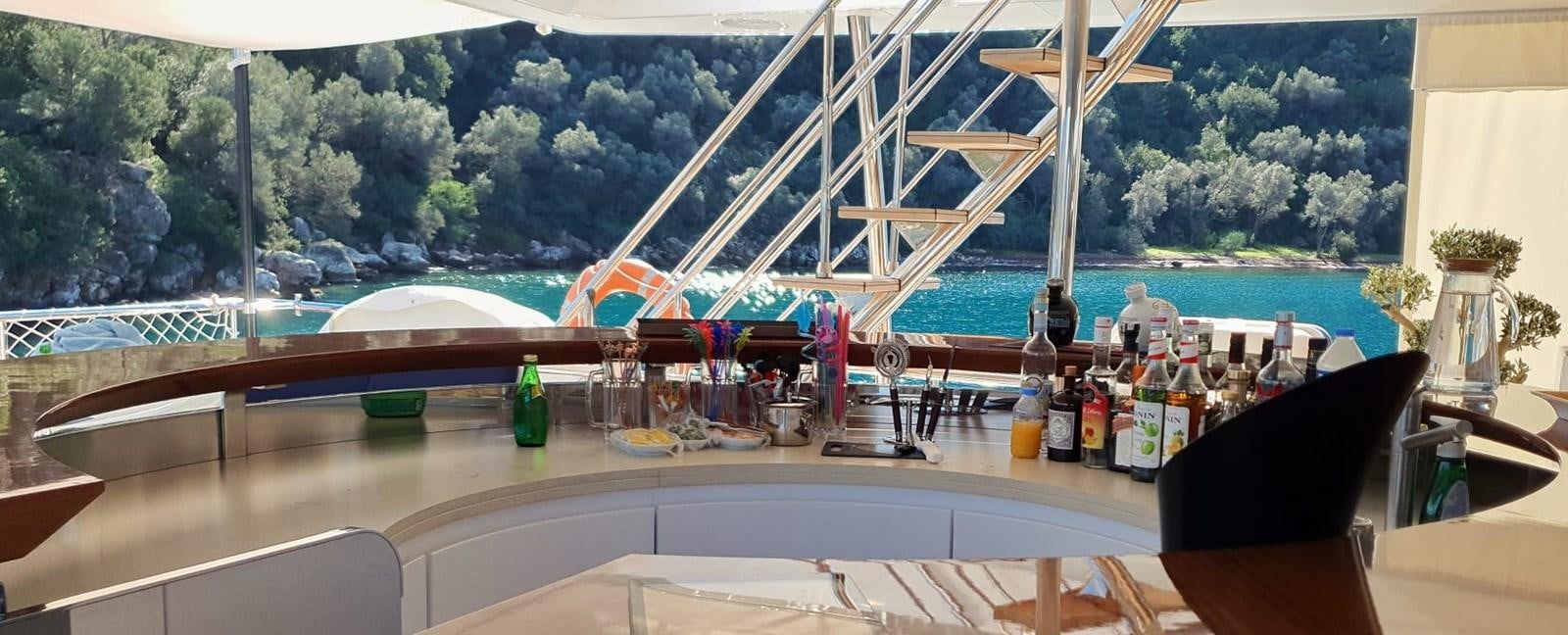 a bar with a view of a beach and water aboard GOLDEN LIFE Yacht for Sale