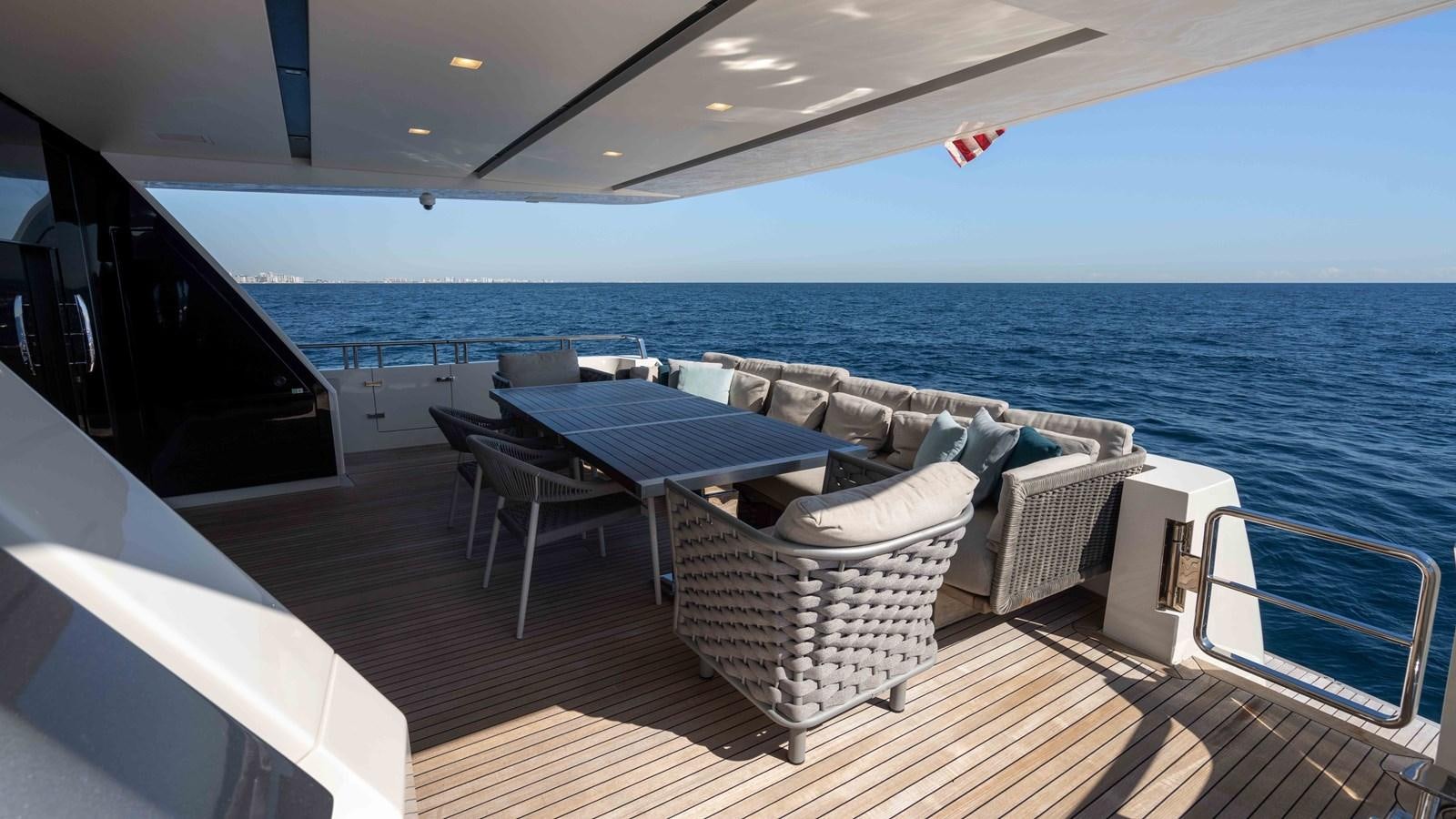a deck with chairs and a table on it aboard 106 FLYBRIDGE Yacht for Sale