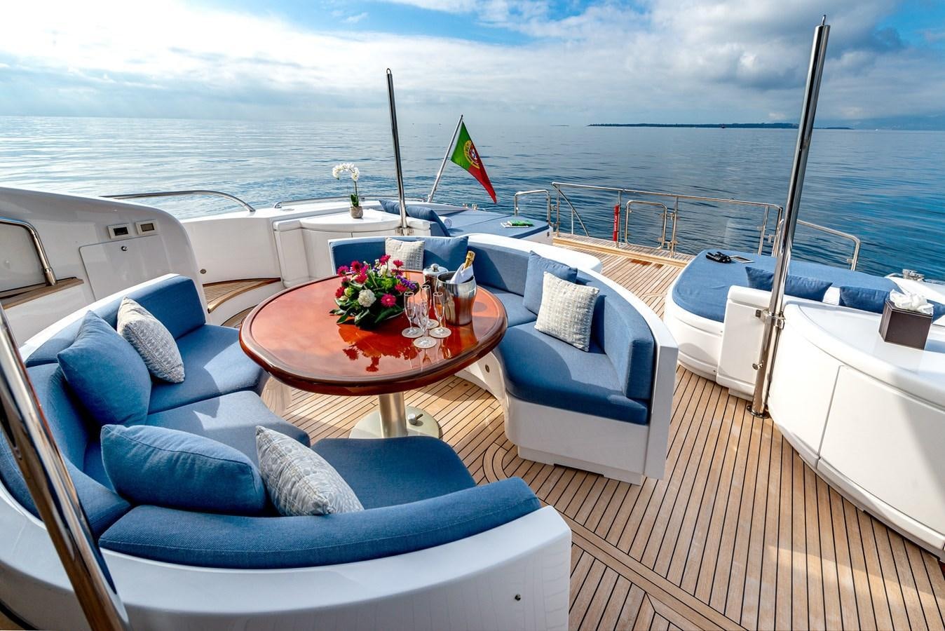 a boat with a table and chairs on a deck with a flag on the side aboard STORM Yacht for Sale