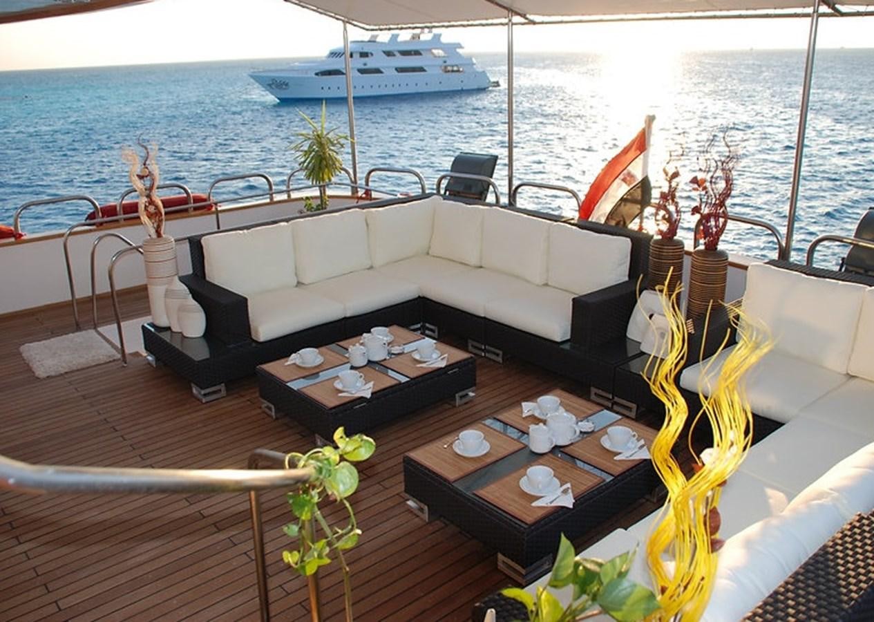 a deck with a couch and a table with plants and a boat in the background aboard 36 M YATCH Yacht for Sale