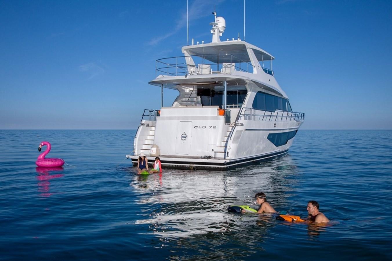 a group of people in a body of water with a large boat in the background aboard CLB72 Yacht for Sale