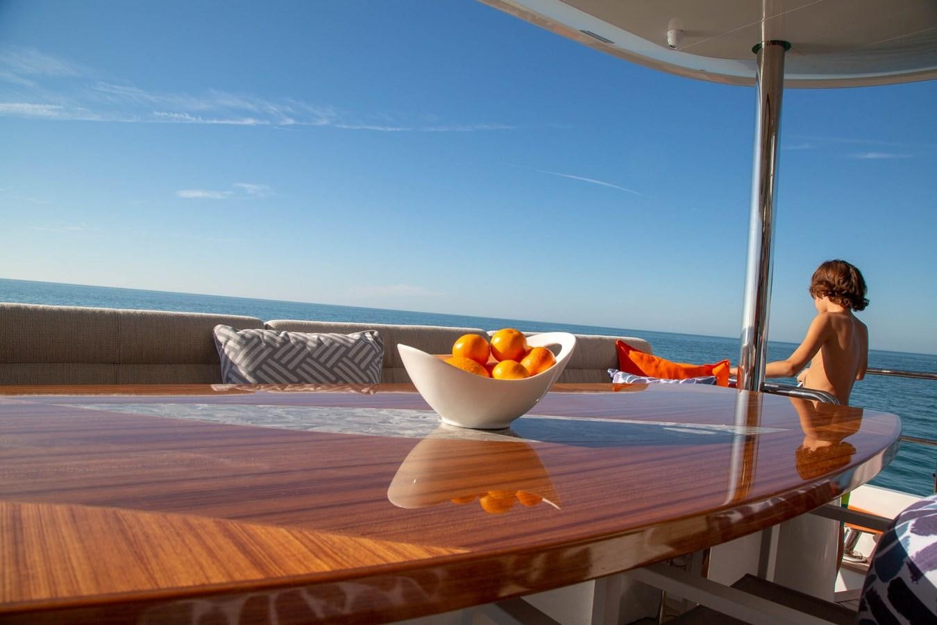 a bowl of oranges on a table by a pool aboard CLB72 Yacht for Sale