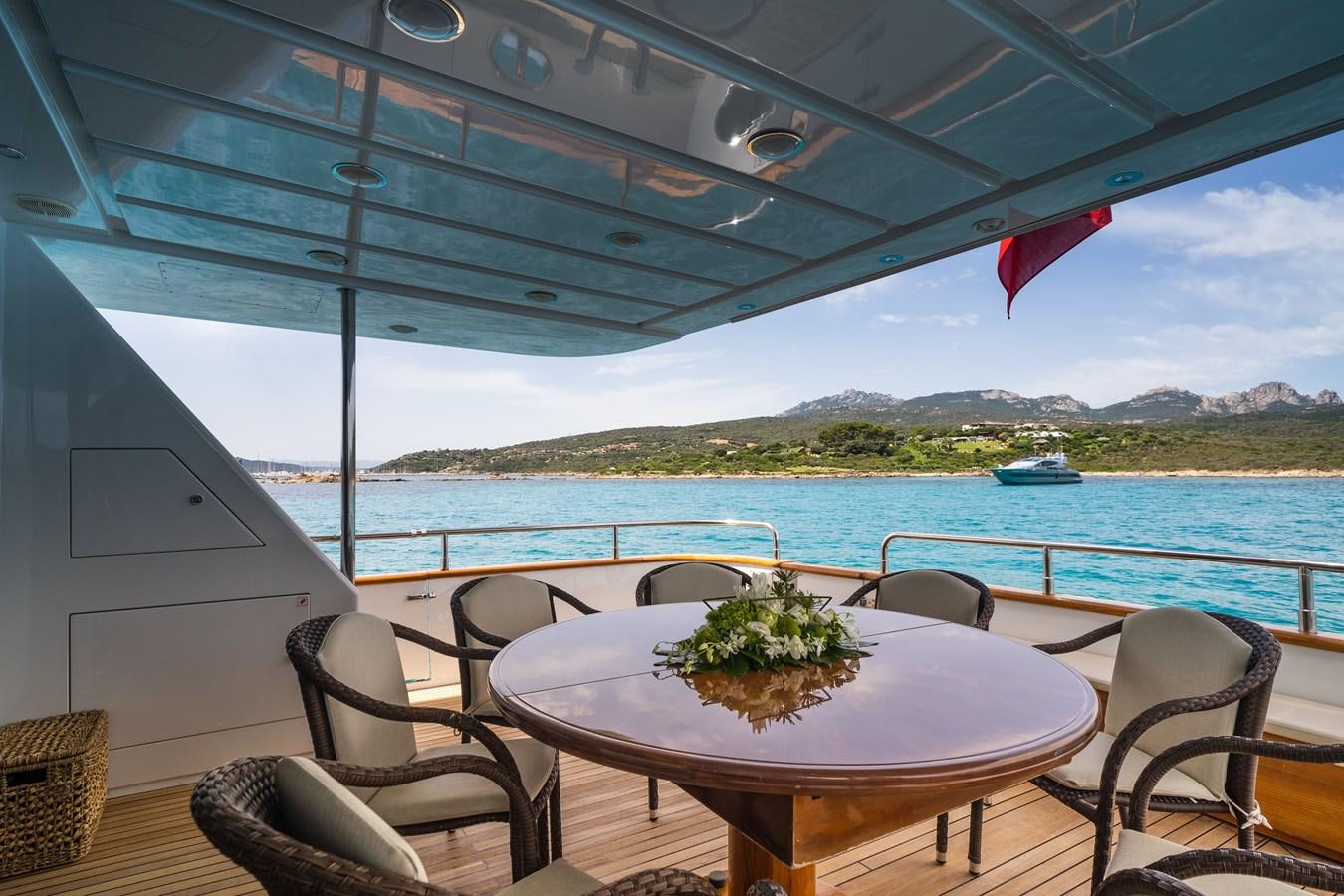 a table and chairs on a deck overlooking a body of water aboard ALEDOUTHO Yacht for Sale