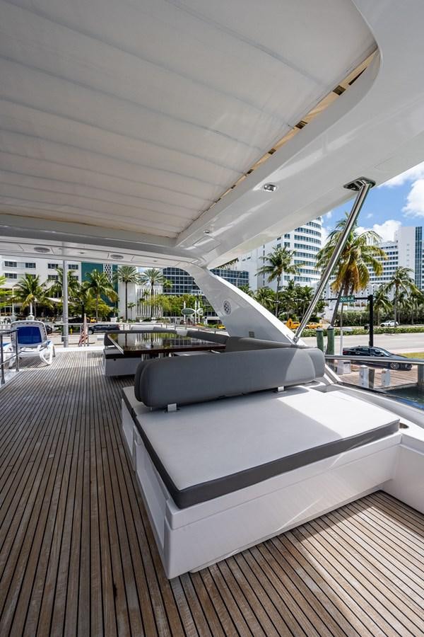 a large white lounge chair on a deck with a large building in the background aboard STAYSEA Yacht for Sale