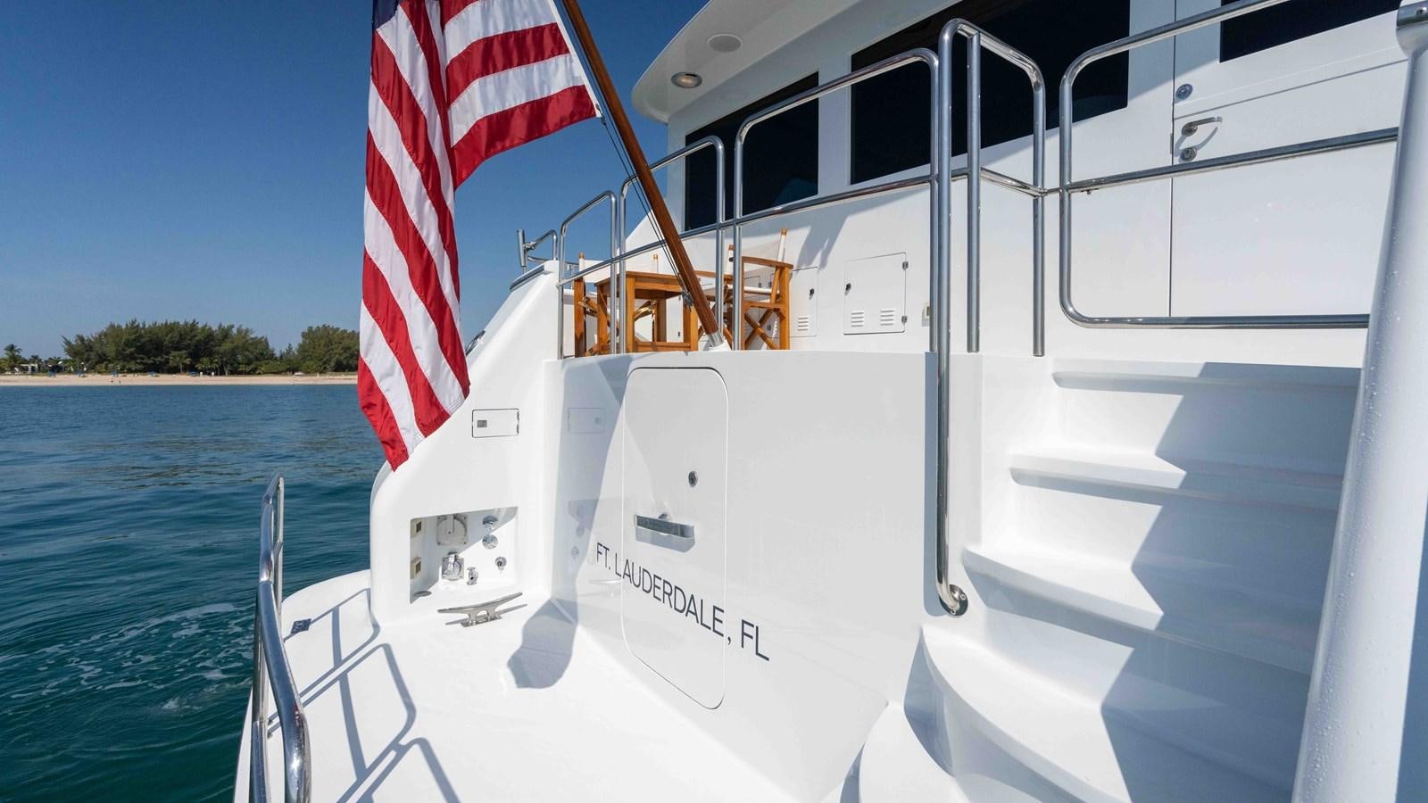 a boat with a flag on the front aboard WELL DONE Yacht for Sale