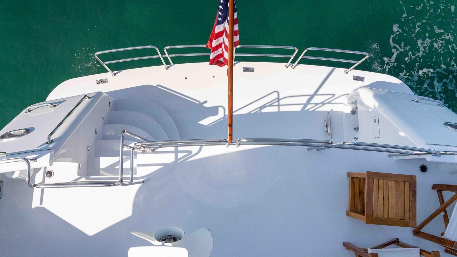 a white boat with a flag on it aboard WELL DONE Yacht for Sale