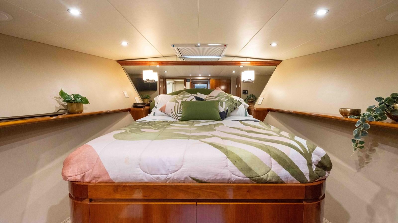 a bed with a green and white comforter and pillows aboard WELL DONE Yacht for Sale