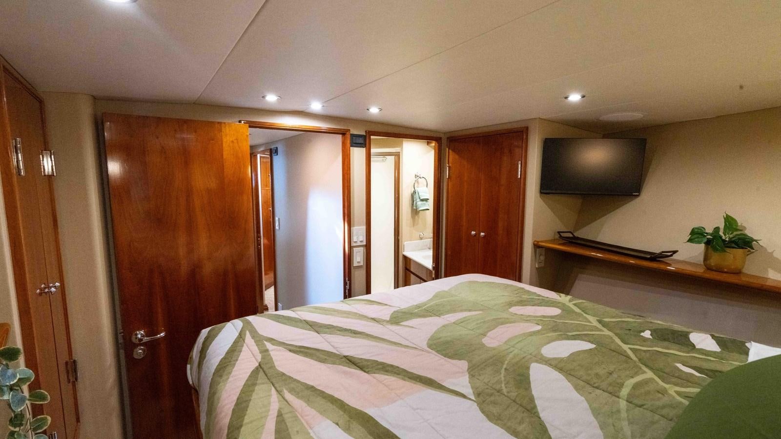 a bedroom with a bed and a television aboard WELL DONE Yacht for Sale