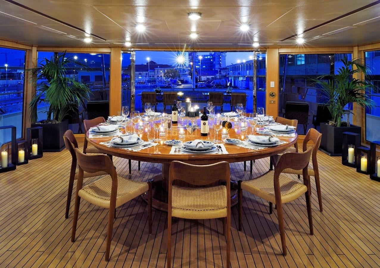 a large dining table with a large room behind it aboard SANOO Yacht for Sale