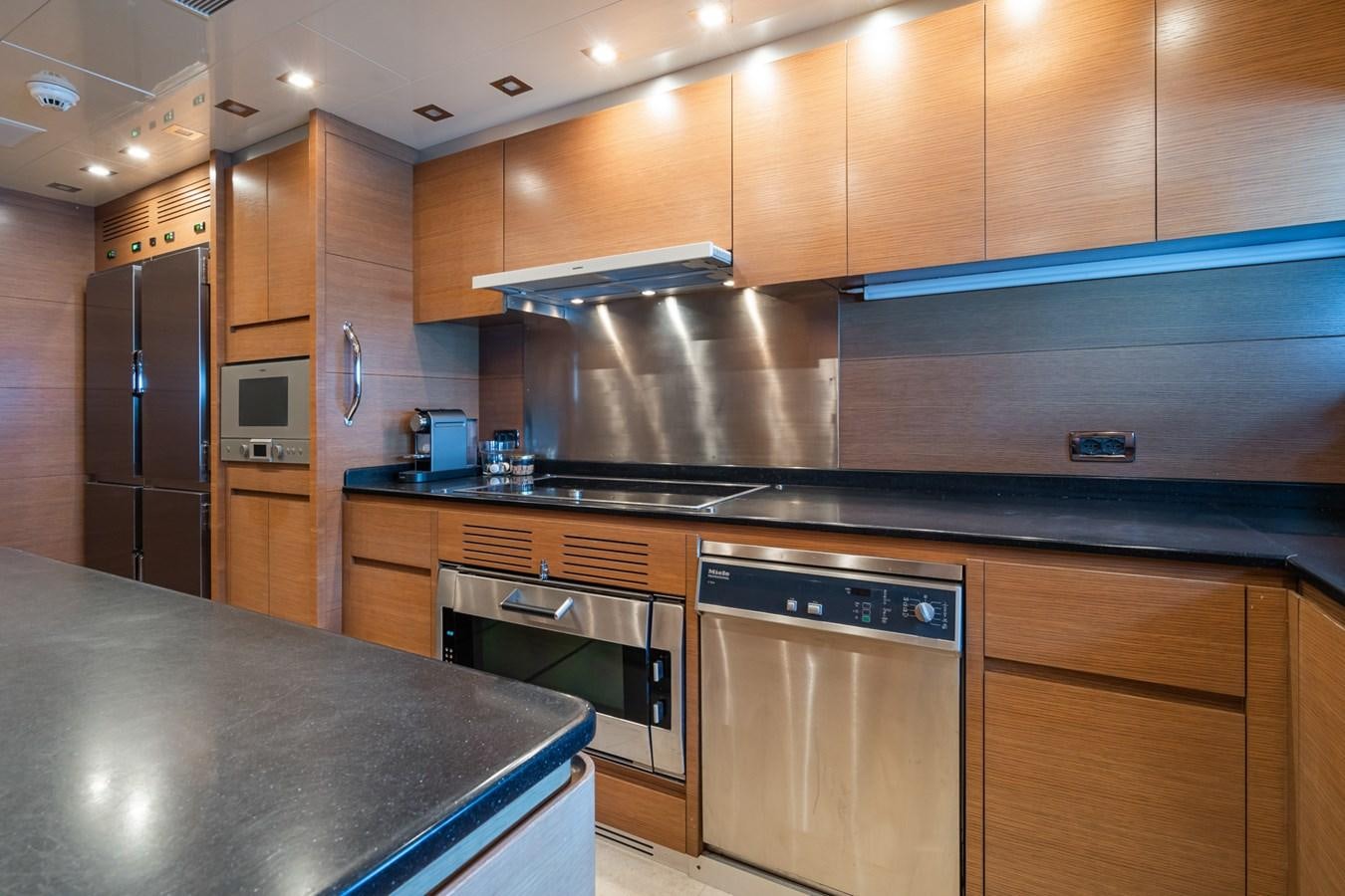 a kitchen with wooden cabinets aboard MANGUSTA 130 Yacht for Sale