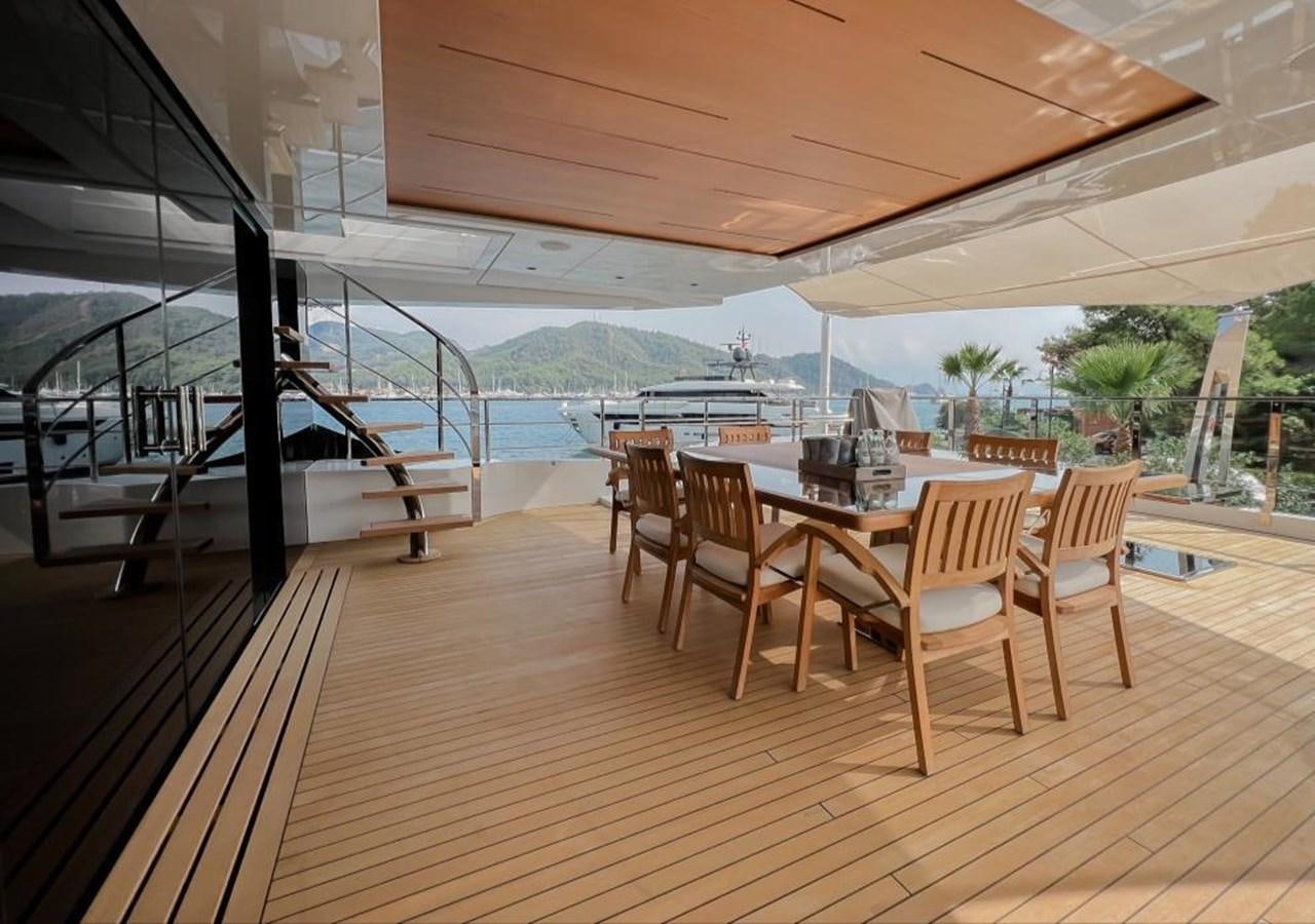 a wood table and chairs on a deck with a view of the water aboard SUNNY Yacht for Sale