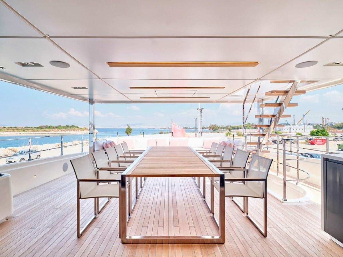 a wooden table and chairs on a deck by the water aboard "THIRTY SEVEN Yacht for Sale