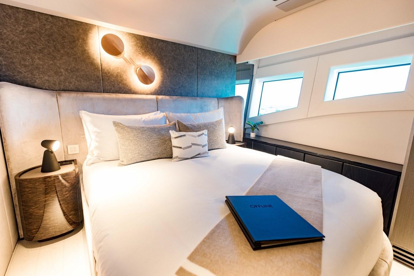 a bed with a blue book on it aboard OFFLINE Yacht for Sale