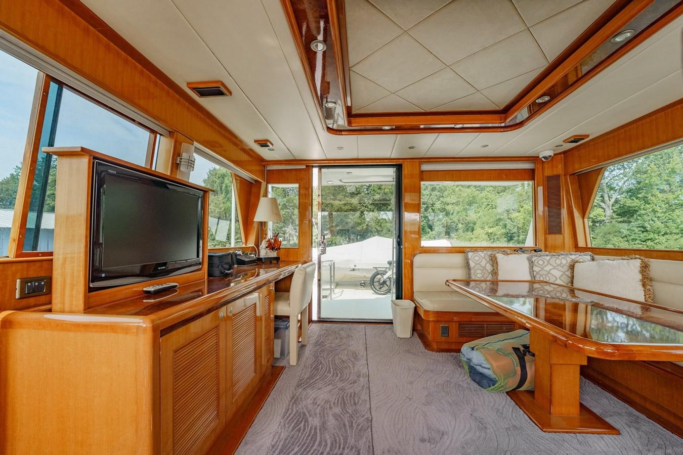 a living room with a tv and a table aboard THREE OF A KIND Yacht for Sale