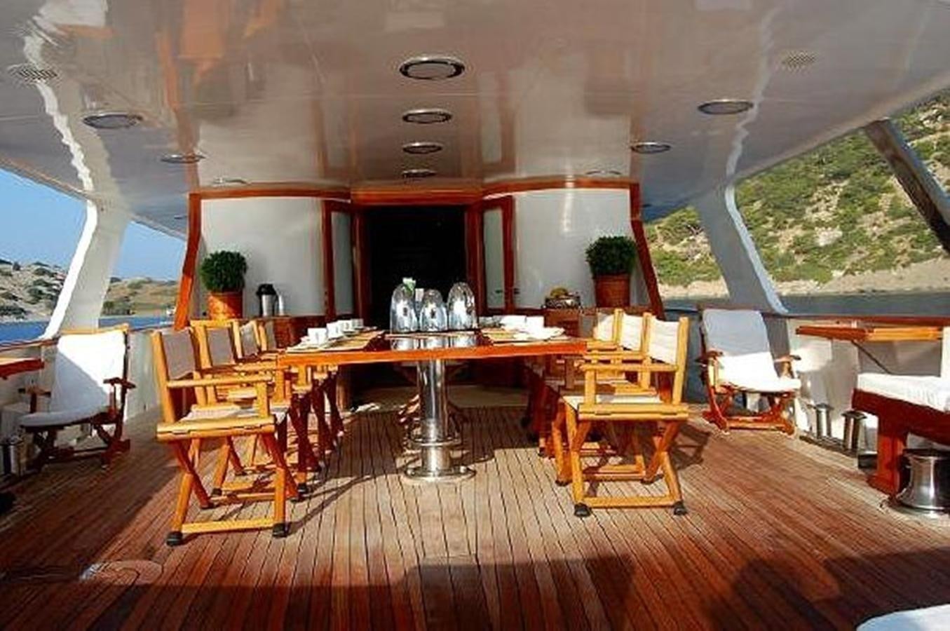 a room with a wood floor and a table with chairs and a window aboard PATRA Yacht for Sale