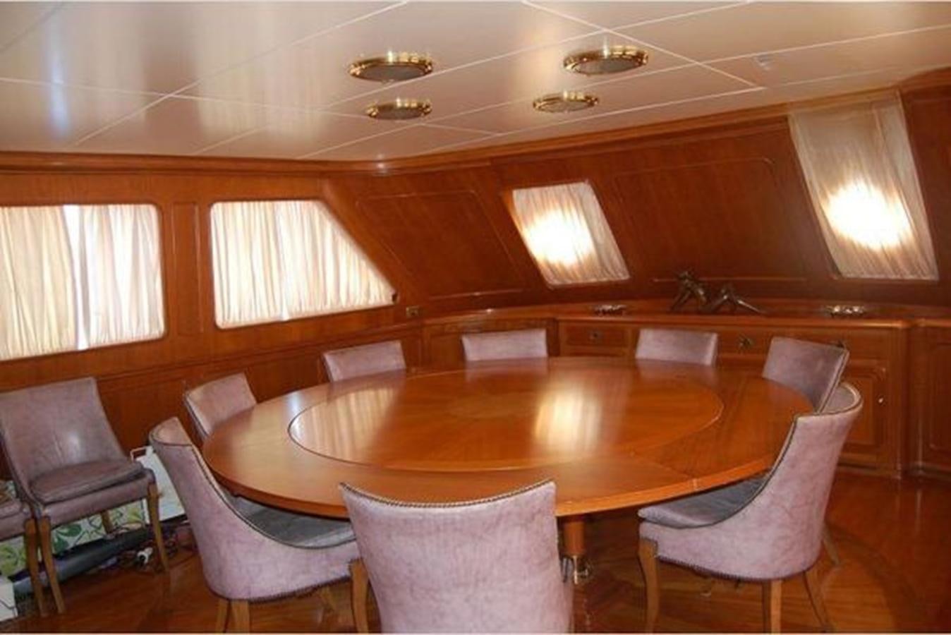 a room with a table chairs and a chandelier aboard PATRA Yacht for Sale