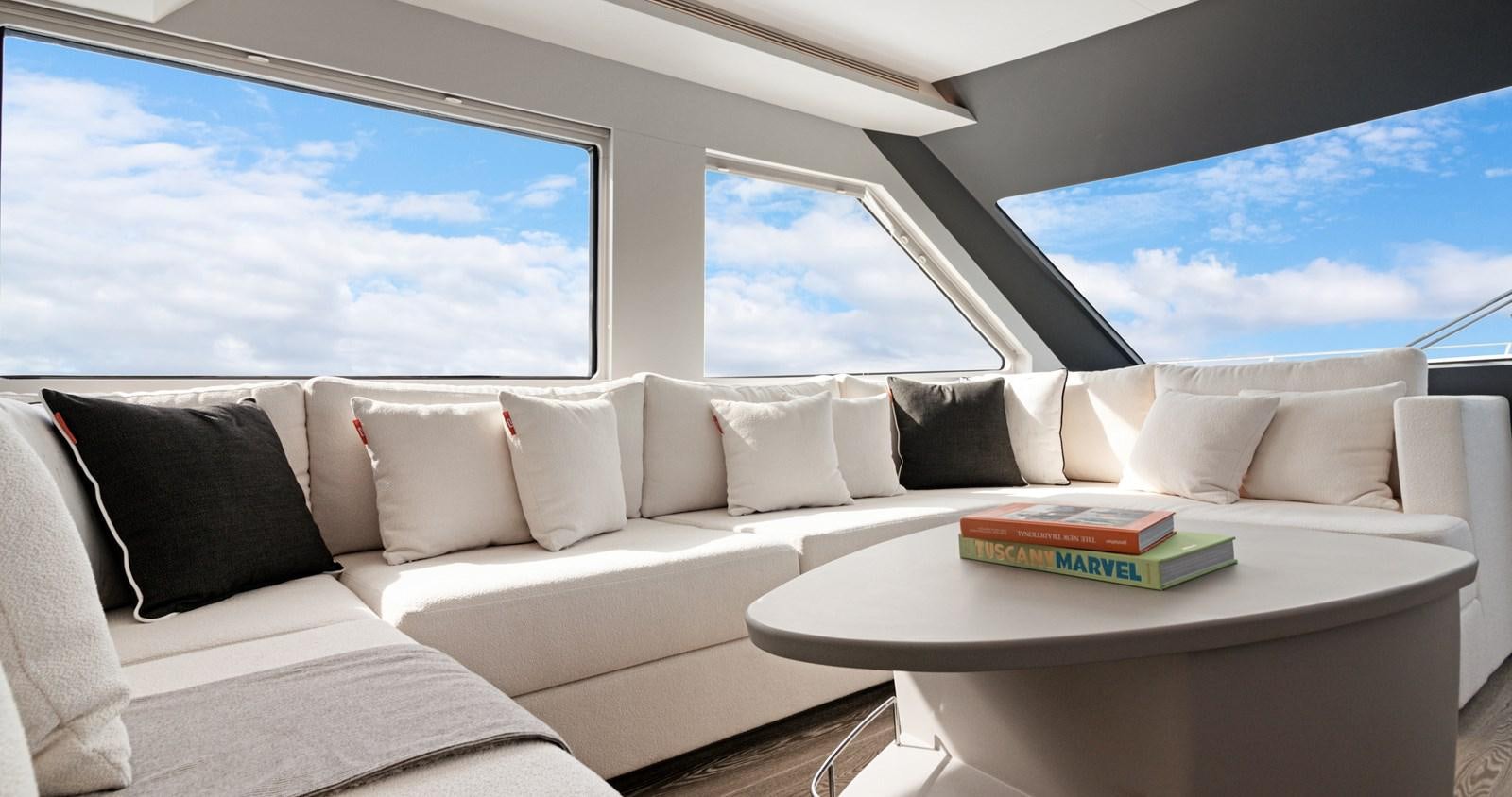 a white couch with pillows and a table with a large window aboard CLB65 Yacht for Sale