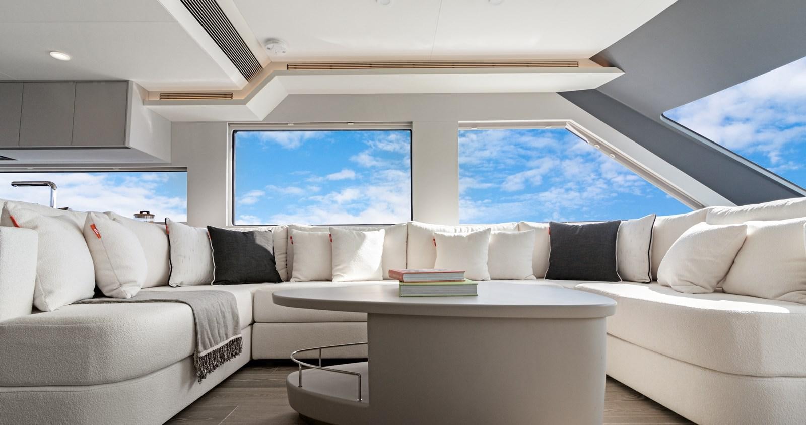 a white couch and a table in a room with a large window aboard CLB65 Yacht for Sale