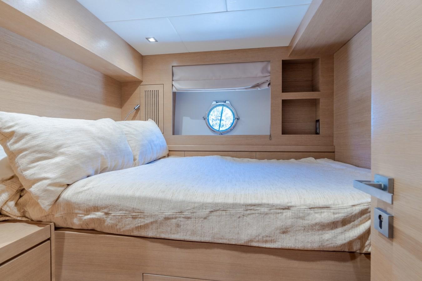 a bed with a blue and white pillow on it aboard PANDA Yacht for Sale