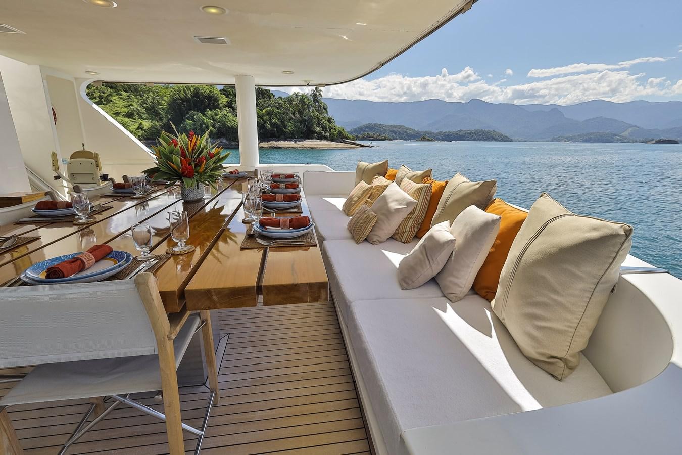 a table with chairs and a large body of water in the background aboard PAPA-GOLFE Yacht for Sale