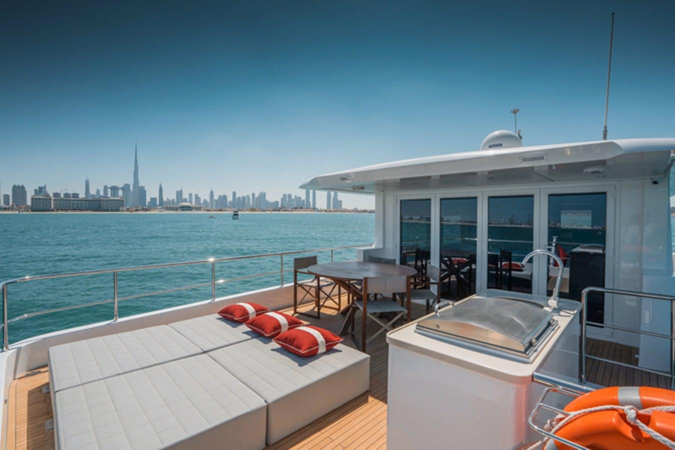 a balcony with a table and chairs on it and a city in the background aboard NOMAD 70 SUV Yacht for Sale