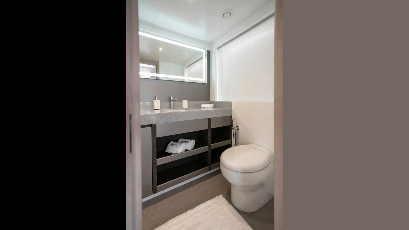 a bathroom with a toilet and a mirror aboard NOMAD 70 SUV Yacht for Sale