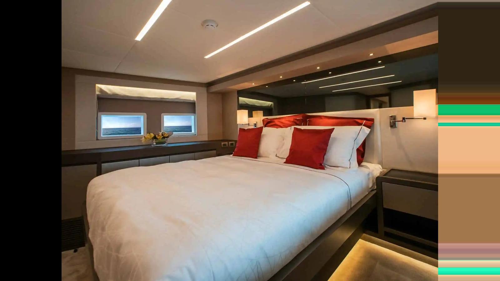 a bed with red pillows aboard NOMAD 70 SUV Yacht for Sale