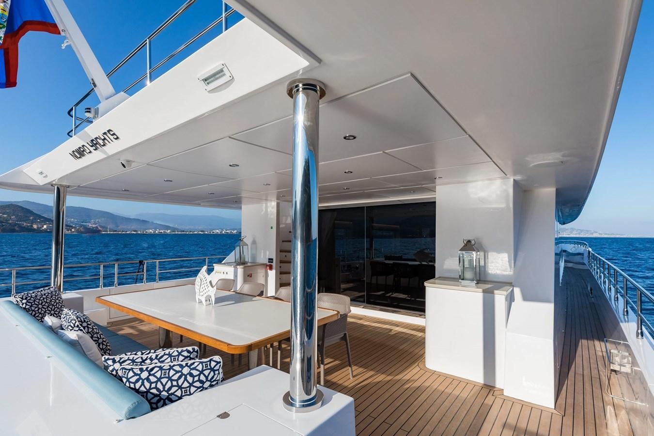 a large white room with a table and chairs and a large body of water aboard NOMAD 95 SUV Yacht for Sale