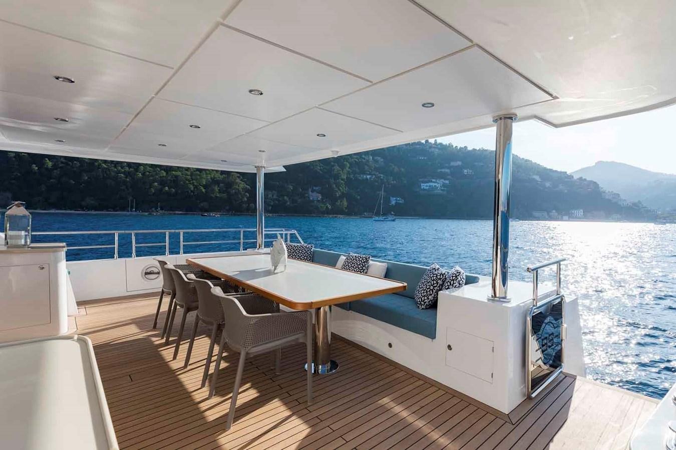 a table and chairs on a deck aboard NOMAD 95 SUV Yacht for Sale