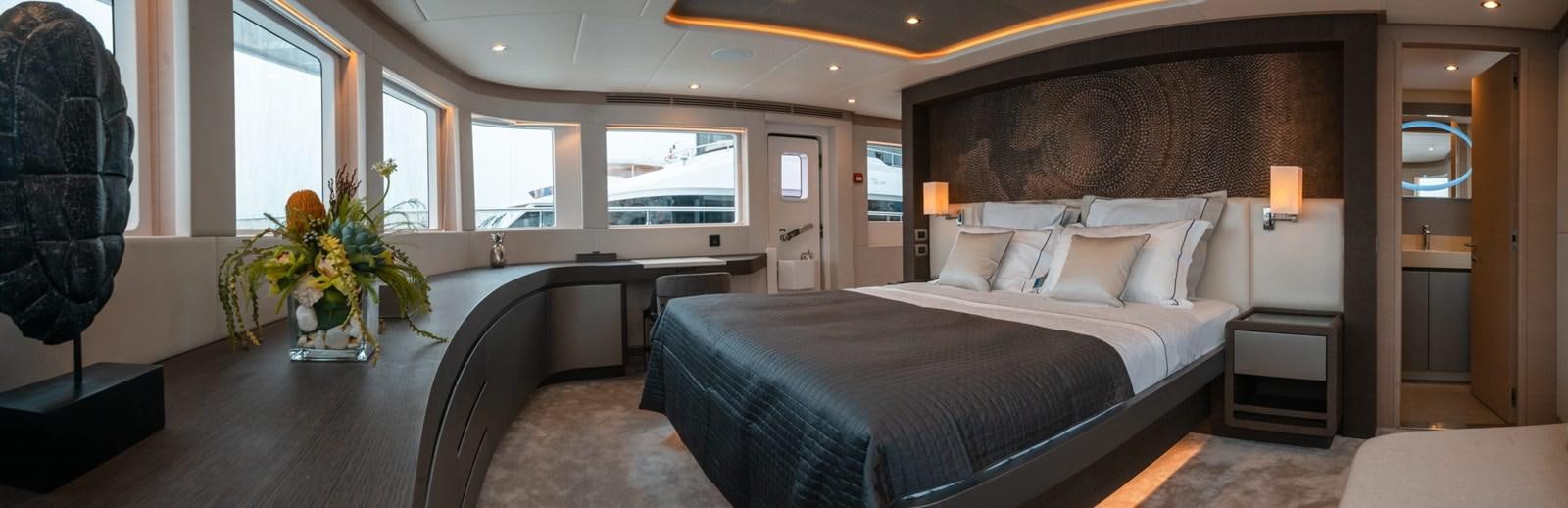 a large bedroom with a bed and a desk aboard NOMAD 95 SUV Yacht for Sale