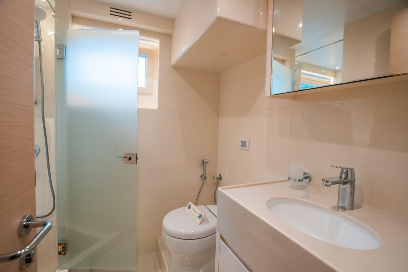 a bathroom with a toilet sink and a mirror aboard NOMAD 95 SUV Yacht for Sale