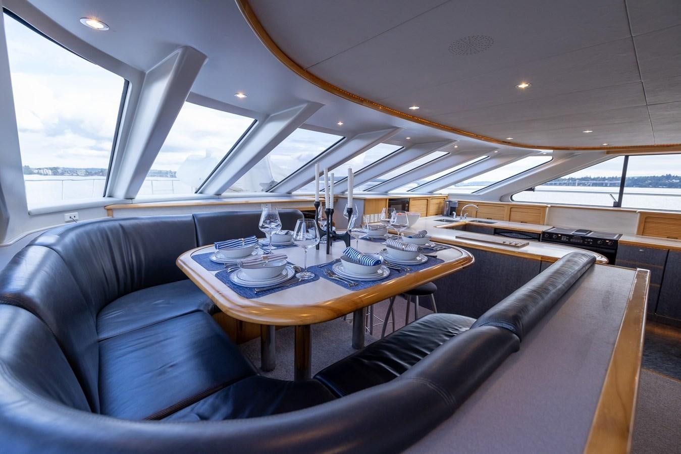 a table with a glass and a chair in a room with a window aboard WHITE LIGHTNING Yacht for Sale