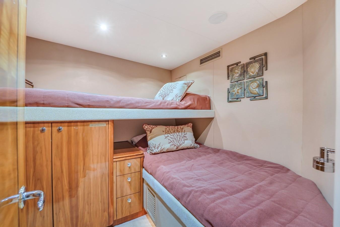 a bedroom with a bed and dresser aboard HATTERAS 80 MOTOR Yacht for Sale