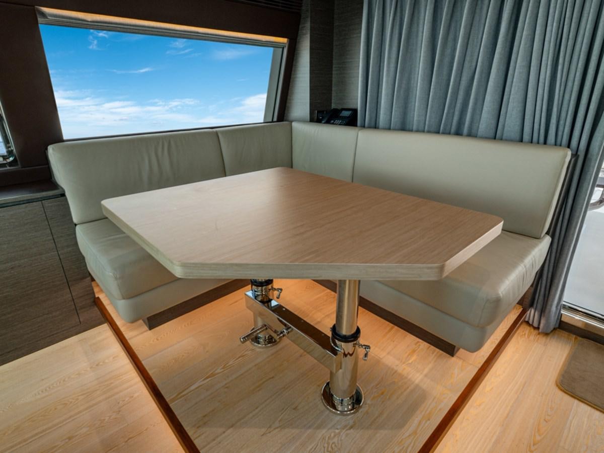 a table with a couch and a window in the background aboard 90 HORIZON Yacht for Sale