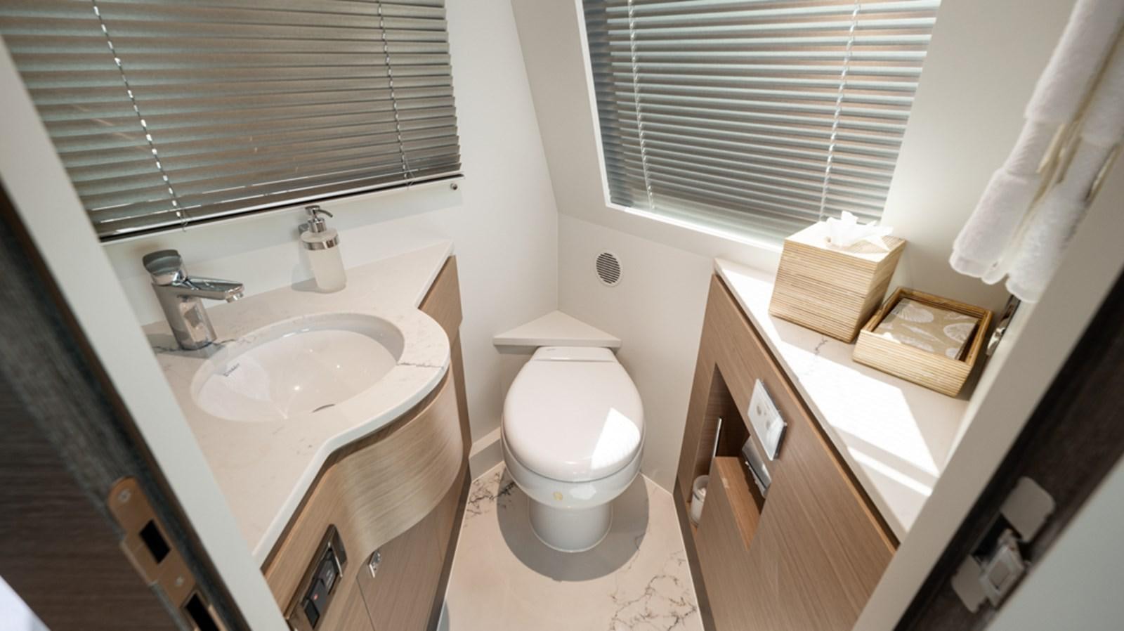 a bathroom with a toilet sink and a window aboard 90 HORIZON Yacht for Sale