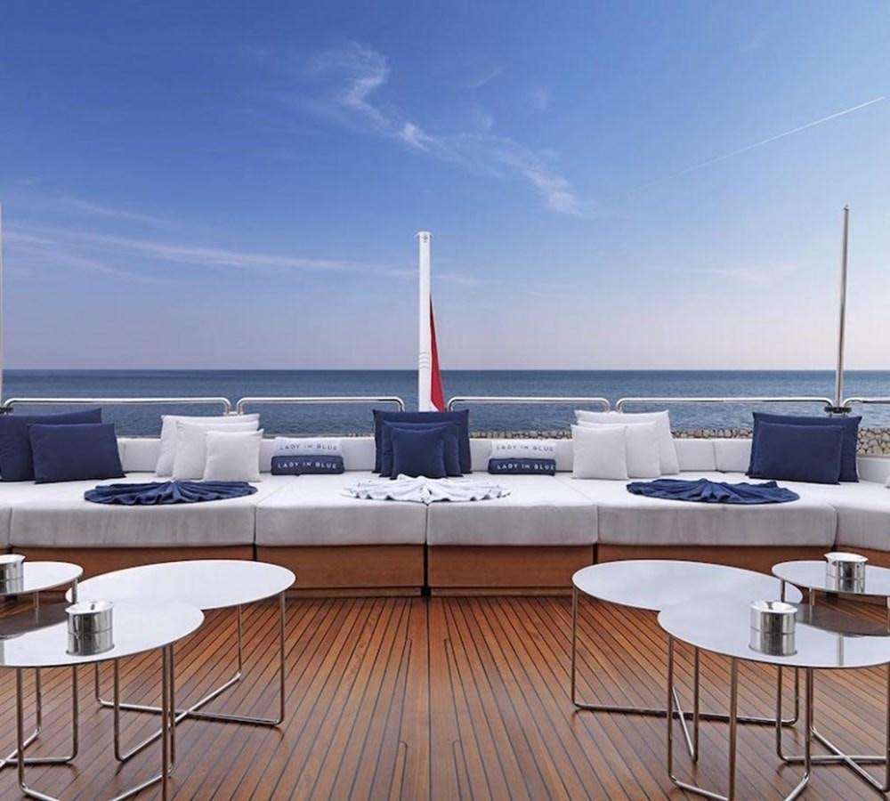 a large white couch with a table and chairs on a deck overlooking the ocean aboard LADY IN BLUE Yacht for Sale