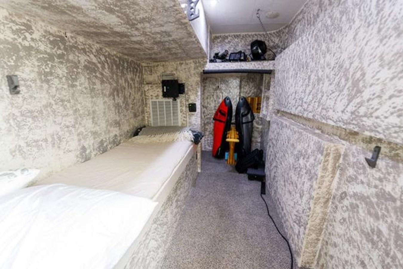 a room with a bed and a wall with a door and a window aboard ROGUE Yacht for Sale