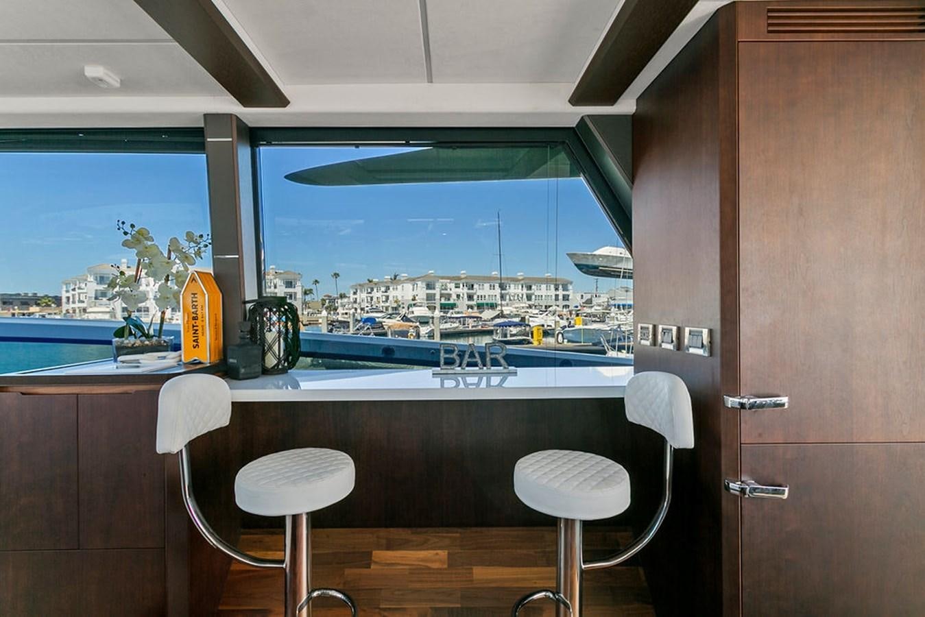 a room with a desk and stools and a window aboard NOKOKO Yacht for Sale