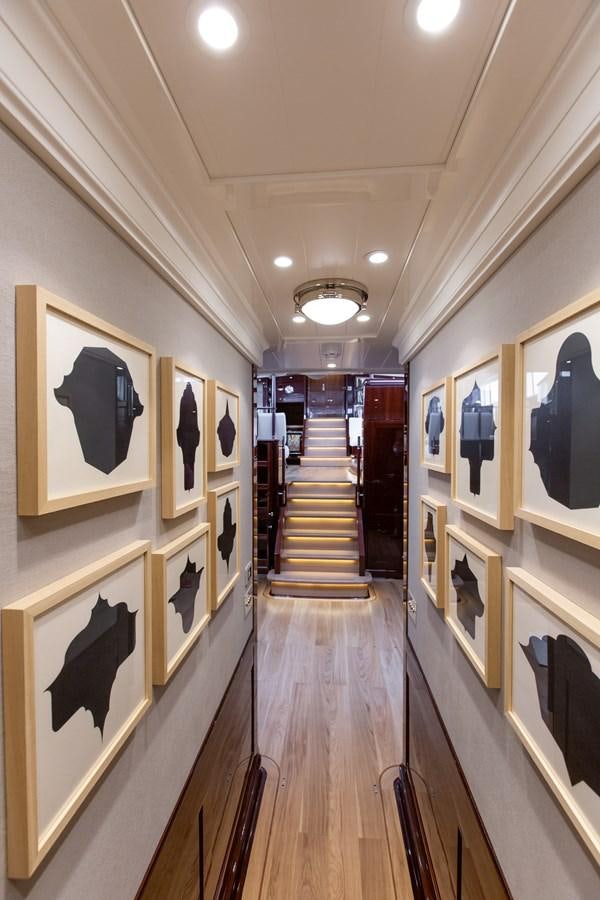 a hallway with paintings on the walls aboard GRACE III Yacht for Sale