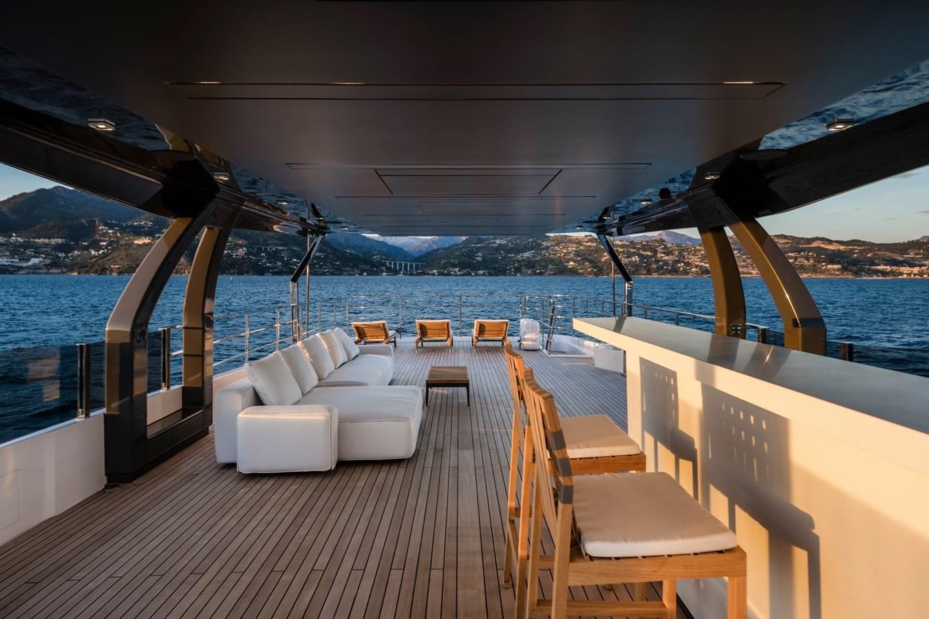 a deck with a view of the ocean and mountains aboard REGINA Yacht for Sale