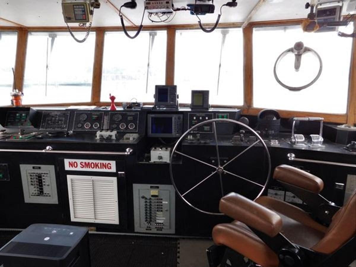a hand holding a steering wheel in a control room aboard 1989 COMMERCIAL FIREBOAT Yacht for Sale