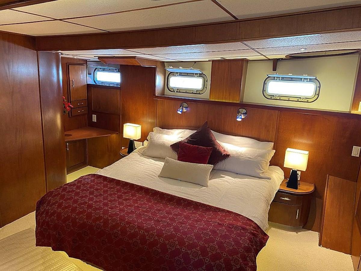 a bed with a red and white comforter and pillows aboard BEAR PAW Yacht for Sale