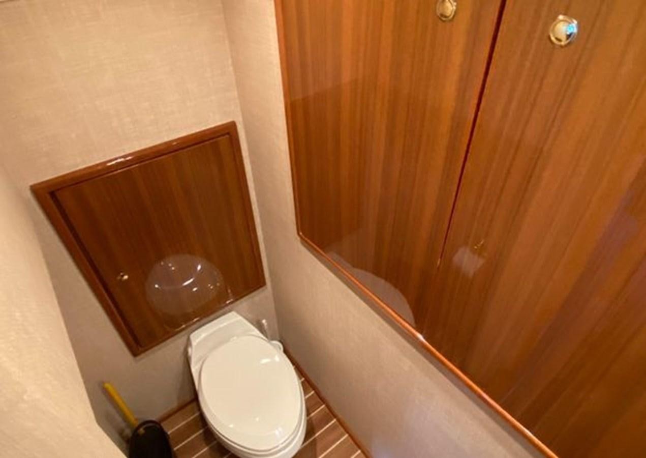 a bathroom with a toilet and a wooden door aboard LIKE WHAT U SEA Yacht for Sale